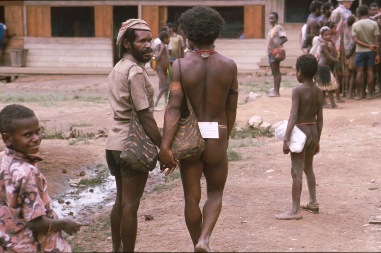 BD/166/60 -
Man in traditional clothes and paper hanging on a thread on his lower back