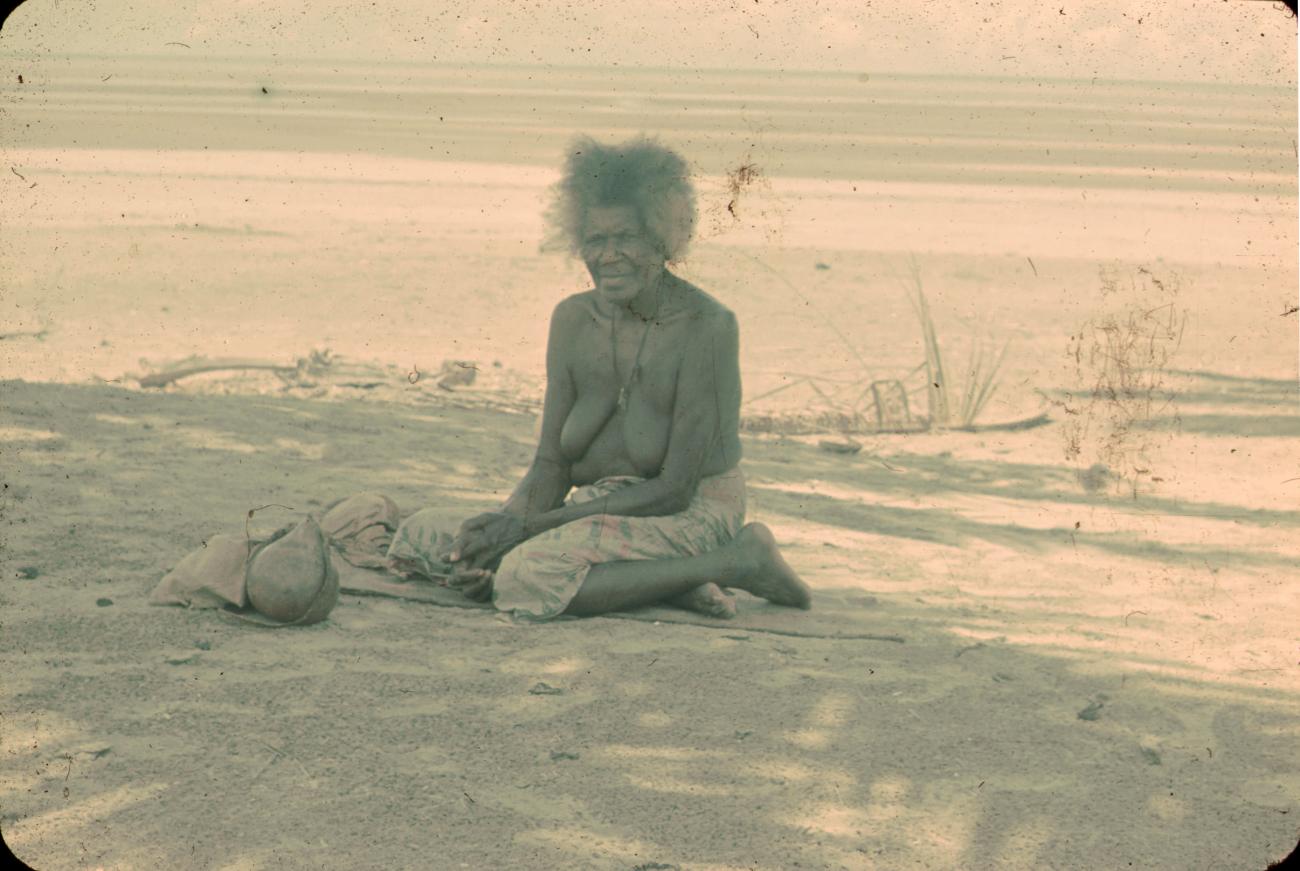 BD/288/165 -
Oude vrouw zit aan het strand