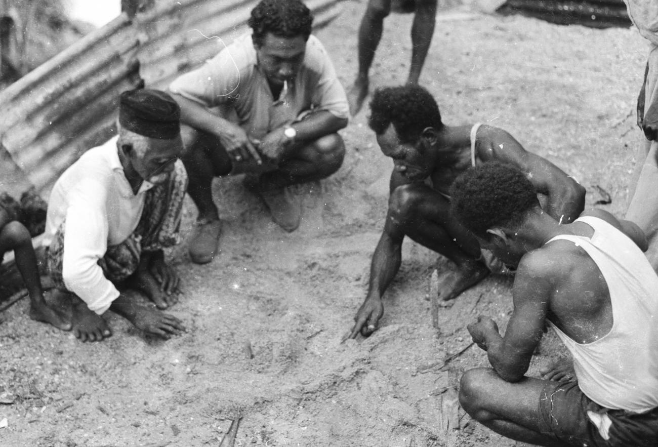 BD/133/1182 -
Papoea-mannen tekenen een kaart in het zand