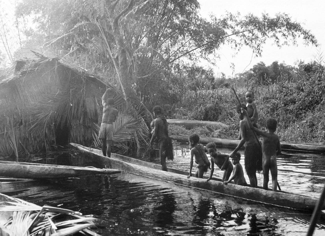 BD/133/299 -
Tocht Merauke-Kepi-Cook: Marind-anim mensen in een prauw bij een hutje
