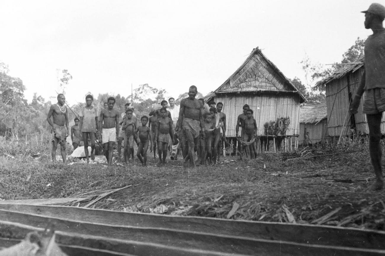 BD/133/445 -
Tocht Merauke-Kepi-Cookrivier vv: Bevolking op oever voor een hut te Kepi