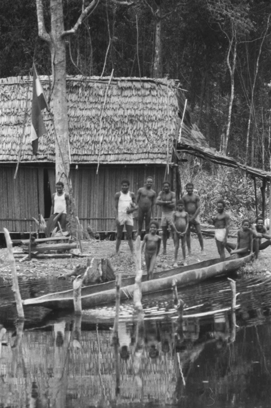 BD/133/52 -
Trip Merauke-Kapi: Marind-anim people standing near a house on the shore