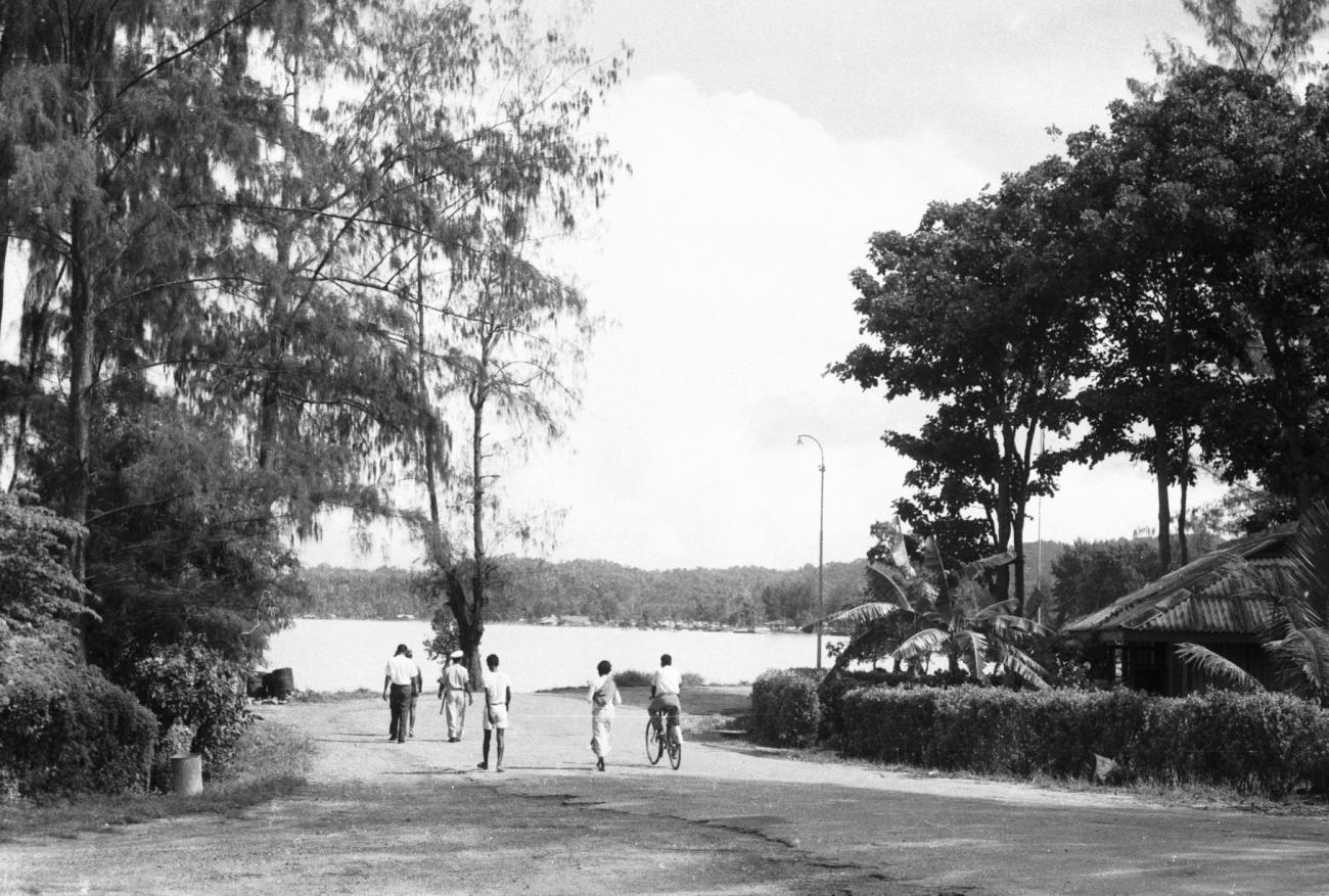 BD/133/899 -
Straatbeeld van weg langs de rivier met lantarenpalen