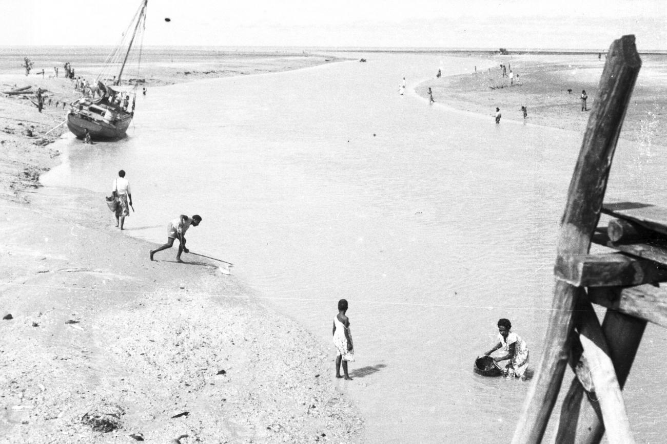 BD/133/945 -
Getijdelandschap met drooggevallen zeilschip en langs de oevers vissende Papoea's