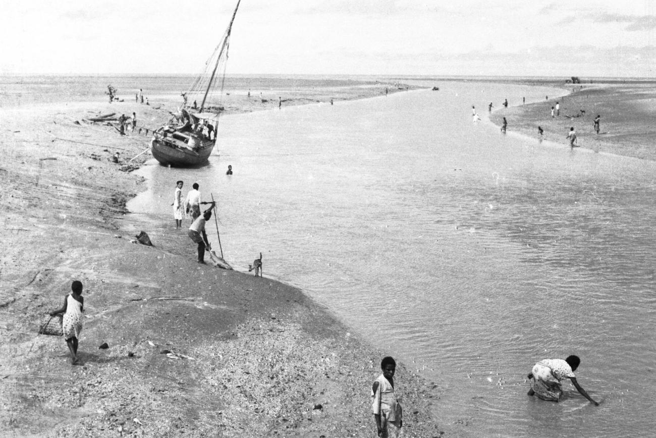 BD/133/946 -
Getijdelandschap met met drooggevallen zeilschip en langs de oevers vissende Papoea's
