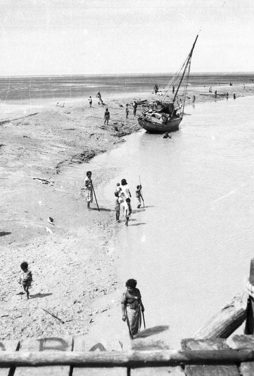 BD/133/948 -
Getijdelandschap met met drooggevallen zeilschip en langs de oevers vissende Papoea's