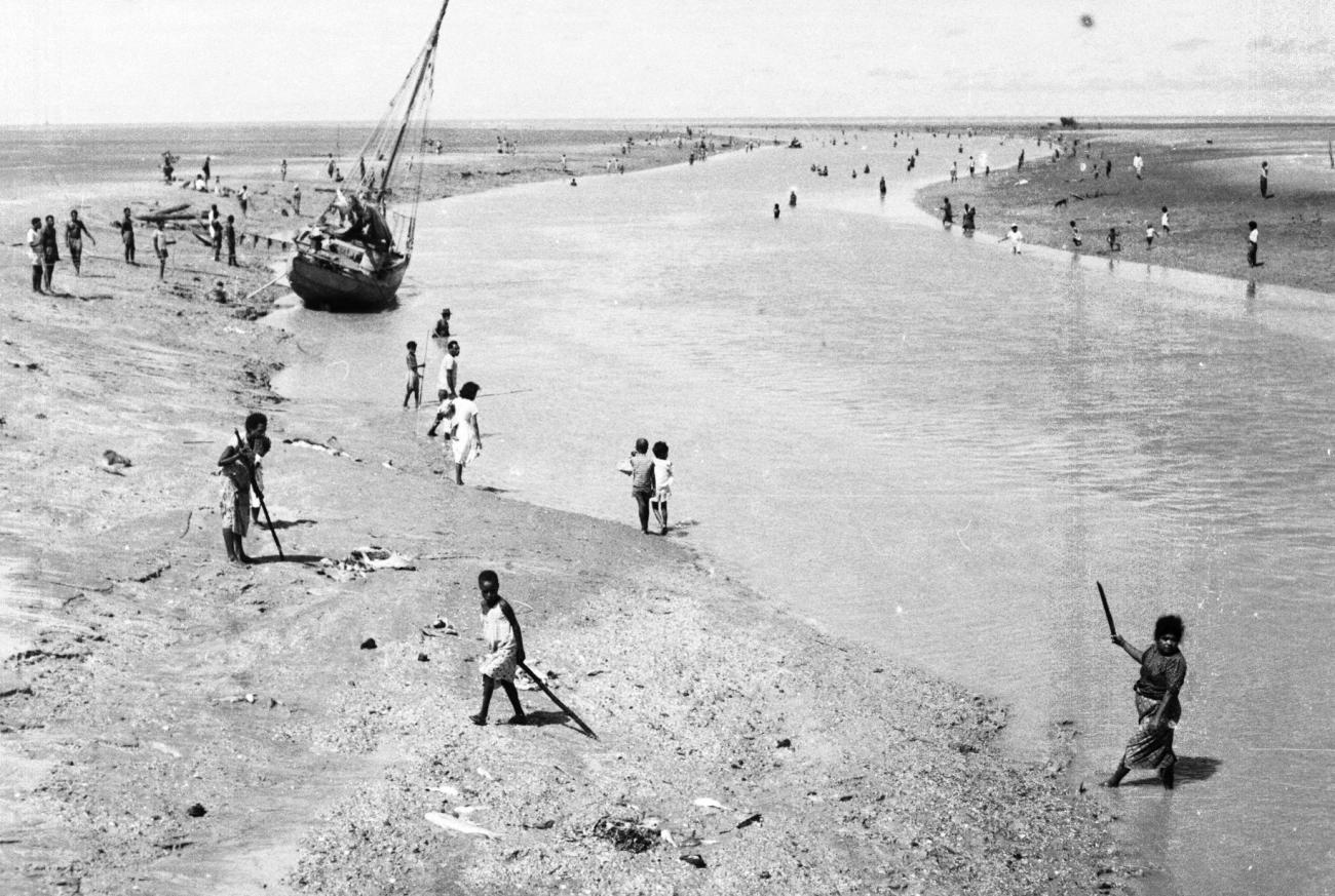 BD/133/949 -
Getijdelandschap met met drooggevallen zeilschip en langs de oevers vissende Papoea's