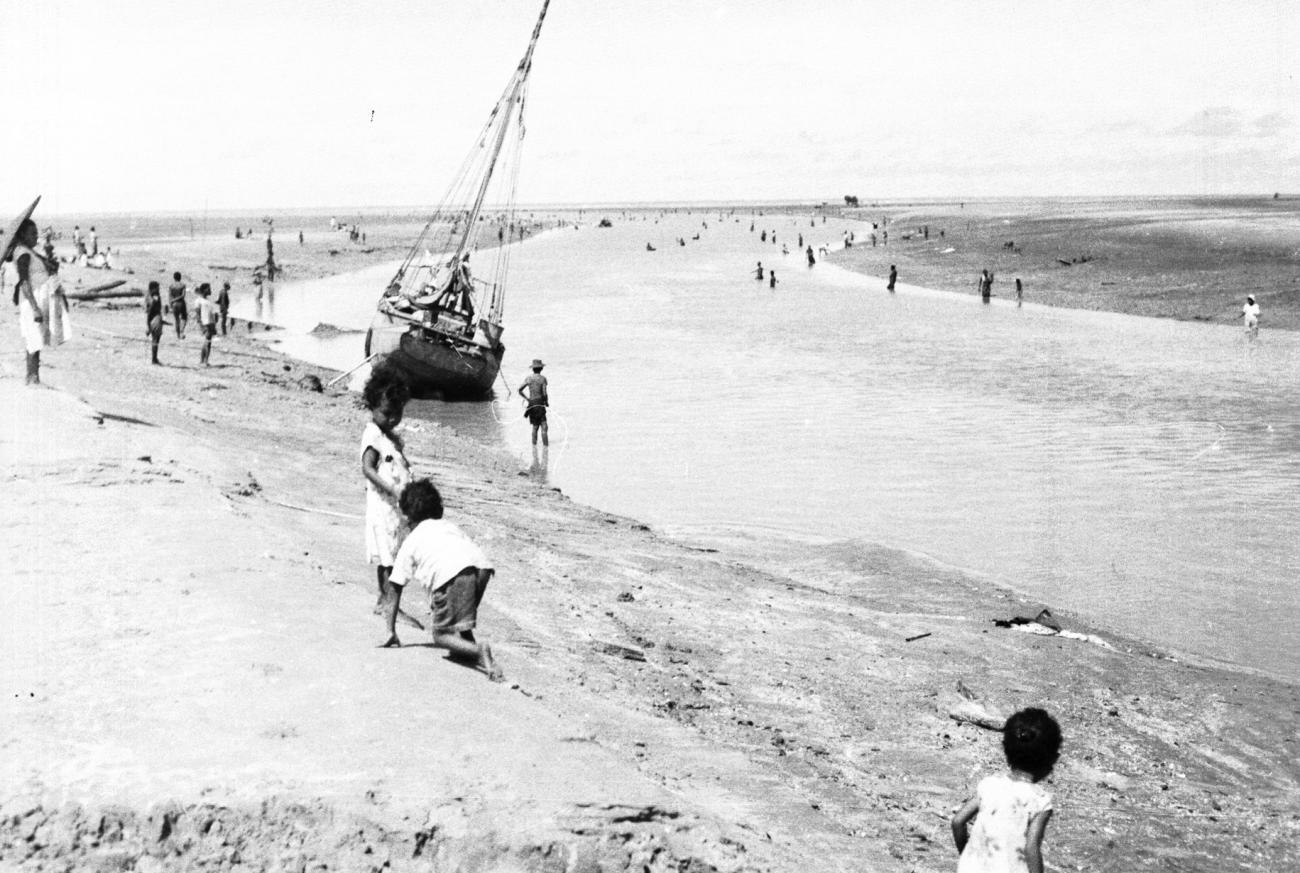 BD/133/950 -
Getijdelandschap met met drooggevallen zeilschip en langs de oevers vissende Papoea's