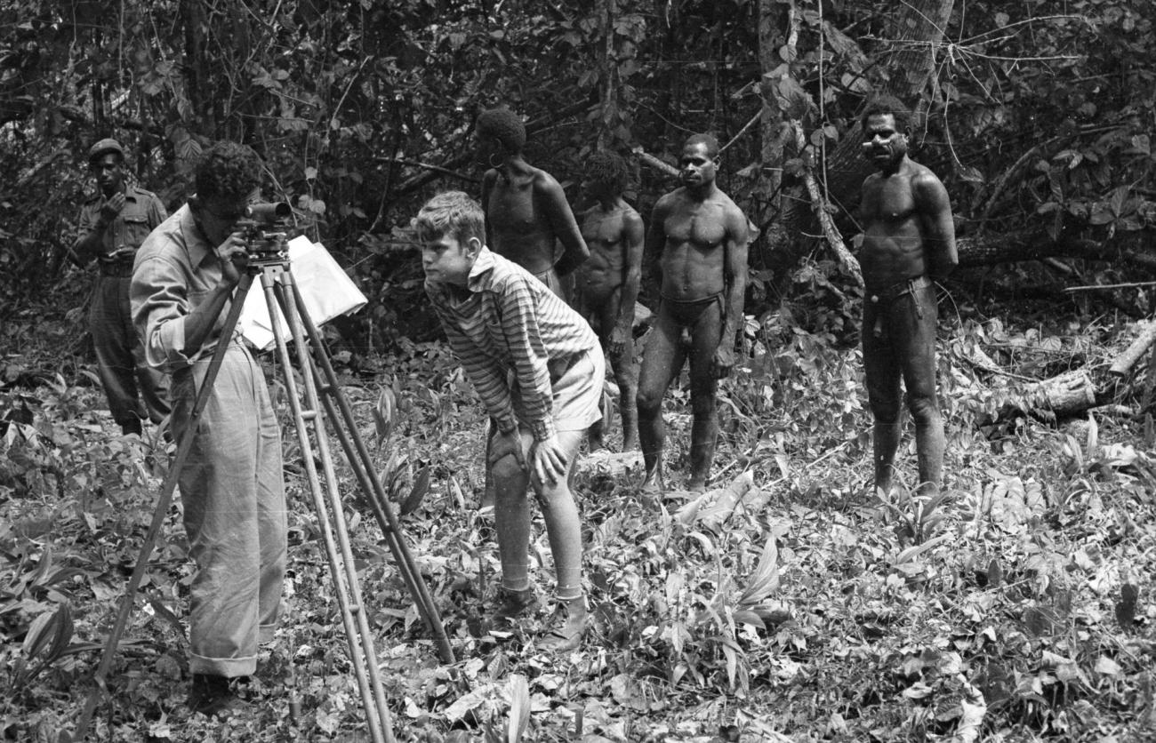 BD/133/985 -
Landmeetkundige met westerse jongen, politieman en Papoea's (Asmat) in het oerwoud