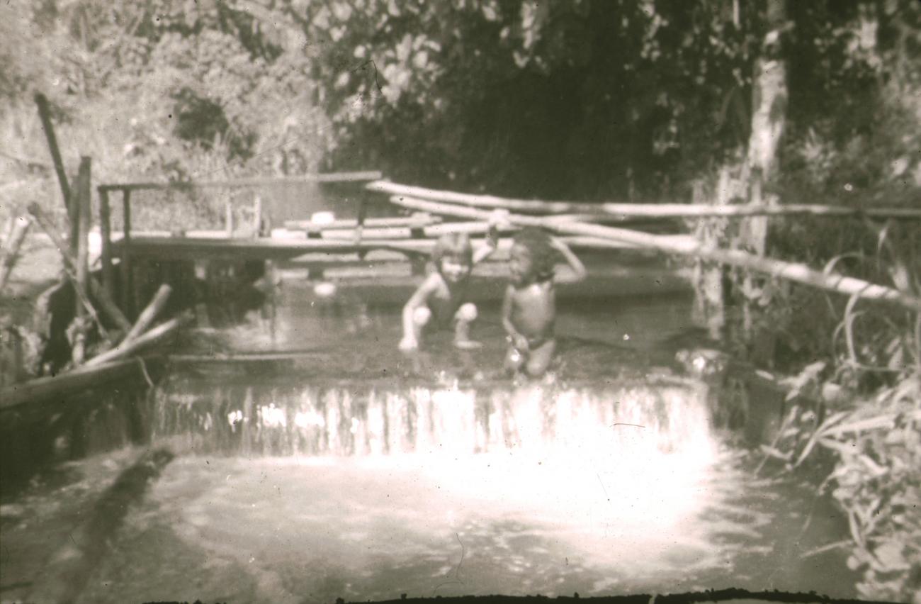 BD/309/315 -
Twee kinderen spelend in het water dat gebruikt wordt voor het bevloeien van de cacaoplantage