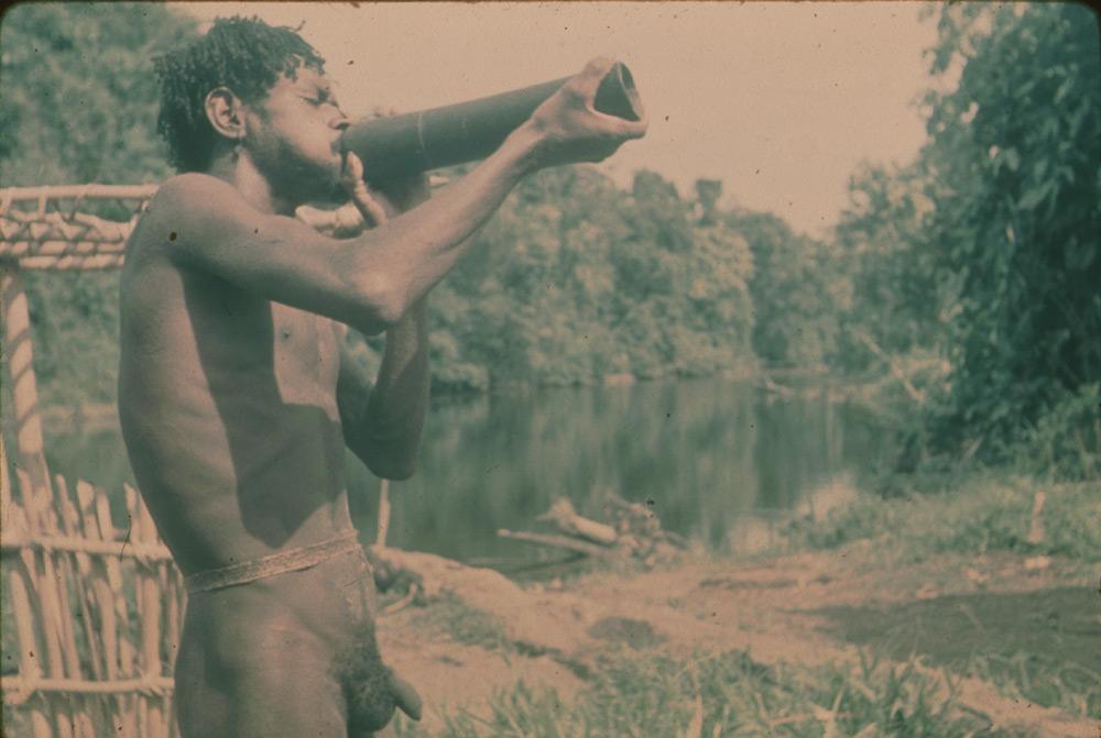 BD/30/43 -
Asmat man next to a river blowing a horn