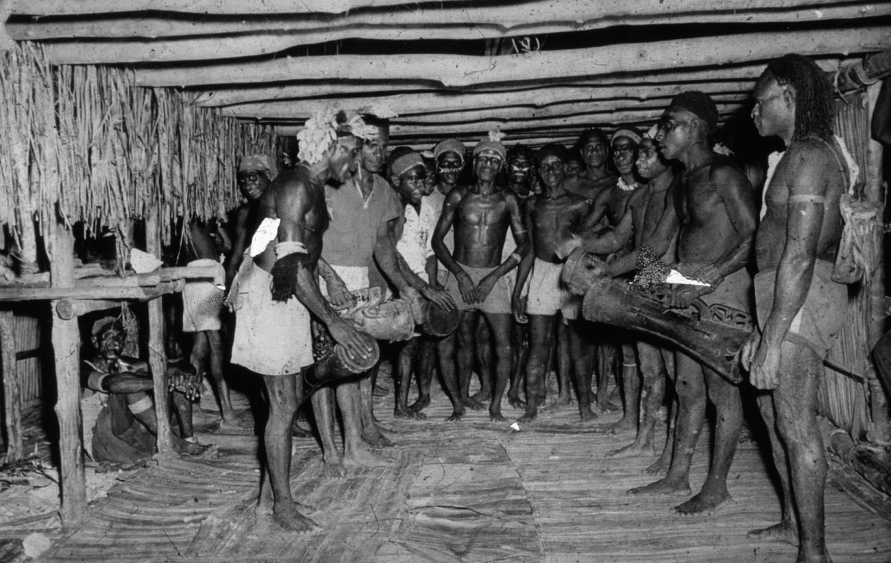 BD/66/183 -
Asmat, mannen met trommels in het mannenhuis