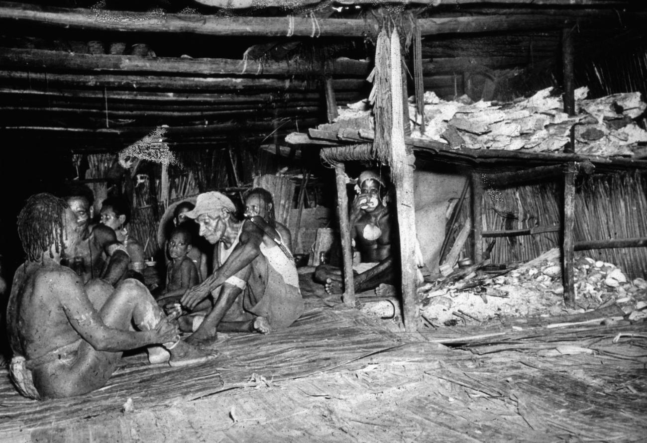 BD/66/185 -
Asmat,mannen en jongens zitten in het mannenhuis