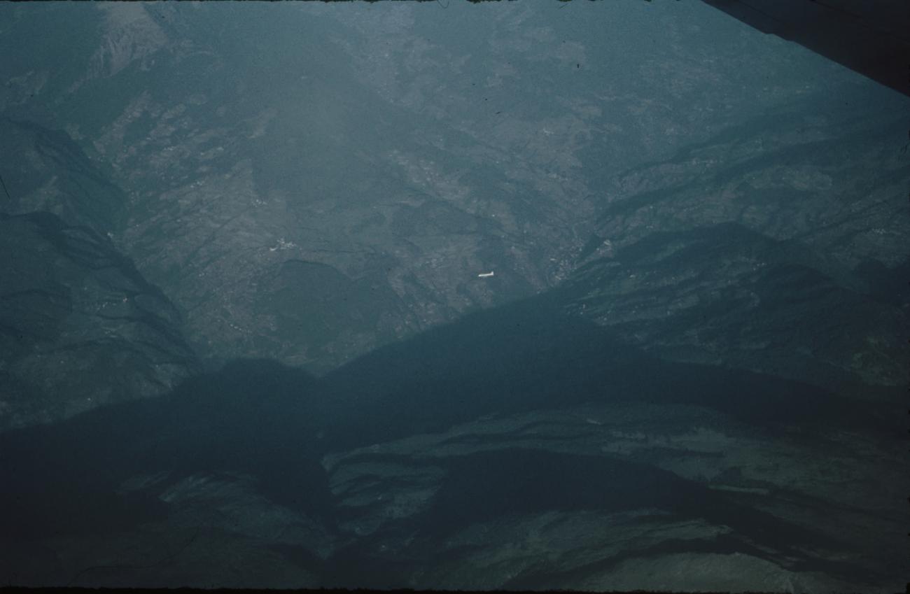 BD/171/11 -
Luchtfoto berglandschap met vliegtuig in verte.