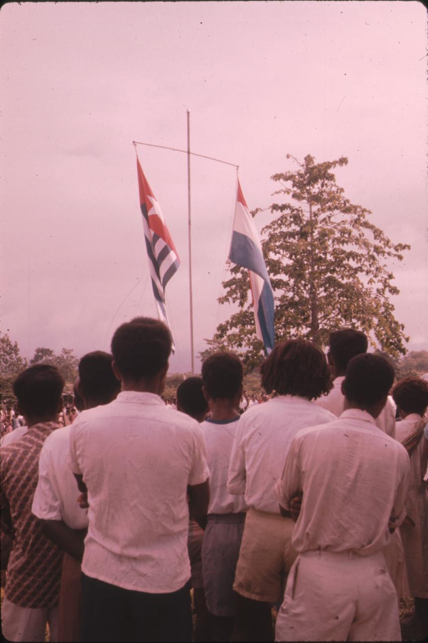 BD/171/24 -
Festiviteit, vlaggenmast met Nederlandse vlag en Papoeavlag.