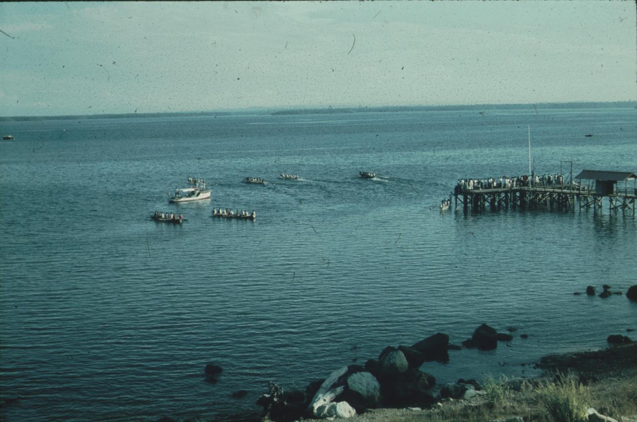BD/171/649 -
Aanlegsteiger met mensen, prauwen en schip in baai.