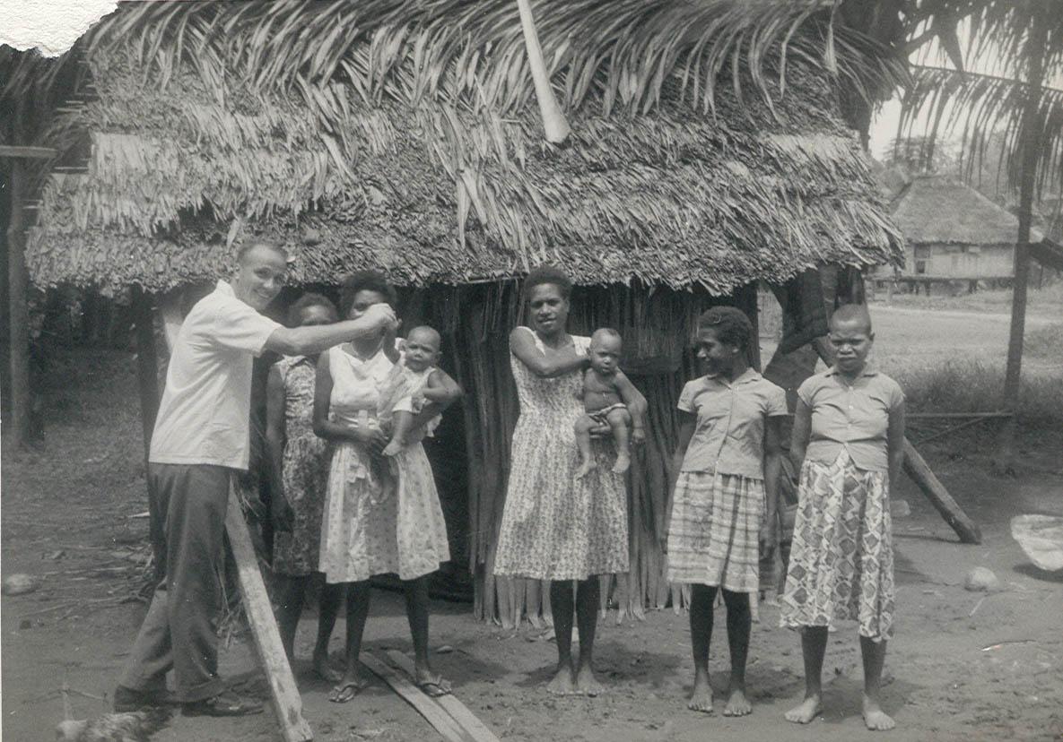 BD/269/1152 -
Franciscaans broeder Henk Blom met Papoea-vrouwen en meisjes poserend voor hun woning