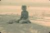 BD/288/165 Oude vrouw zit aan het strand