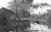 BD/133/290 Tocht Merauke-Kepi-Cook: Hut met prauwen aan het water