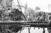 BD/133/293 Tocht Merauke-Kepi-Cook: Hut met prauwen aan het water